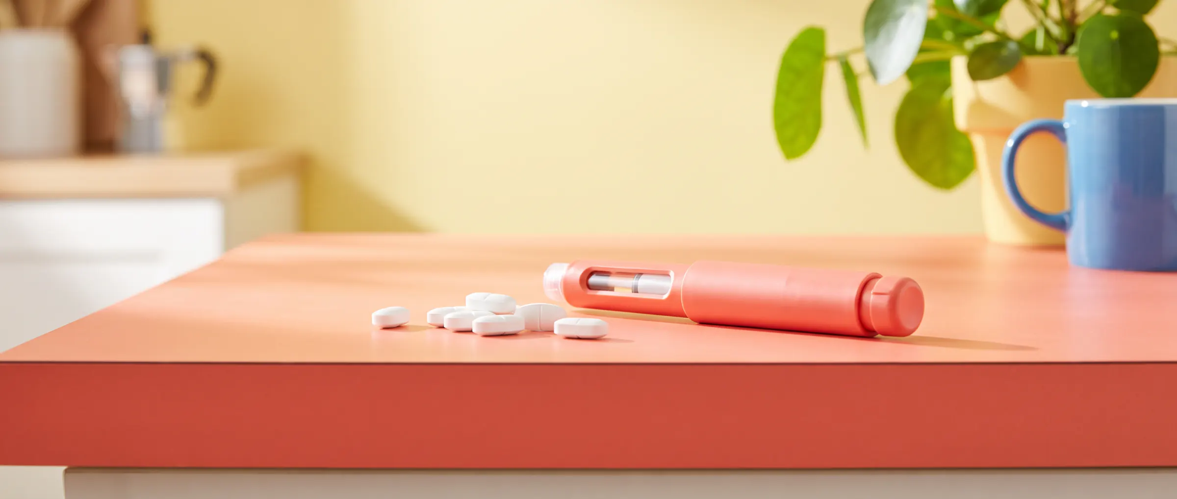 A handful of white tablets beside an injection pen on a sunny coral table