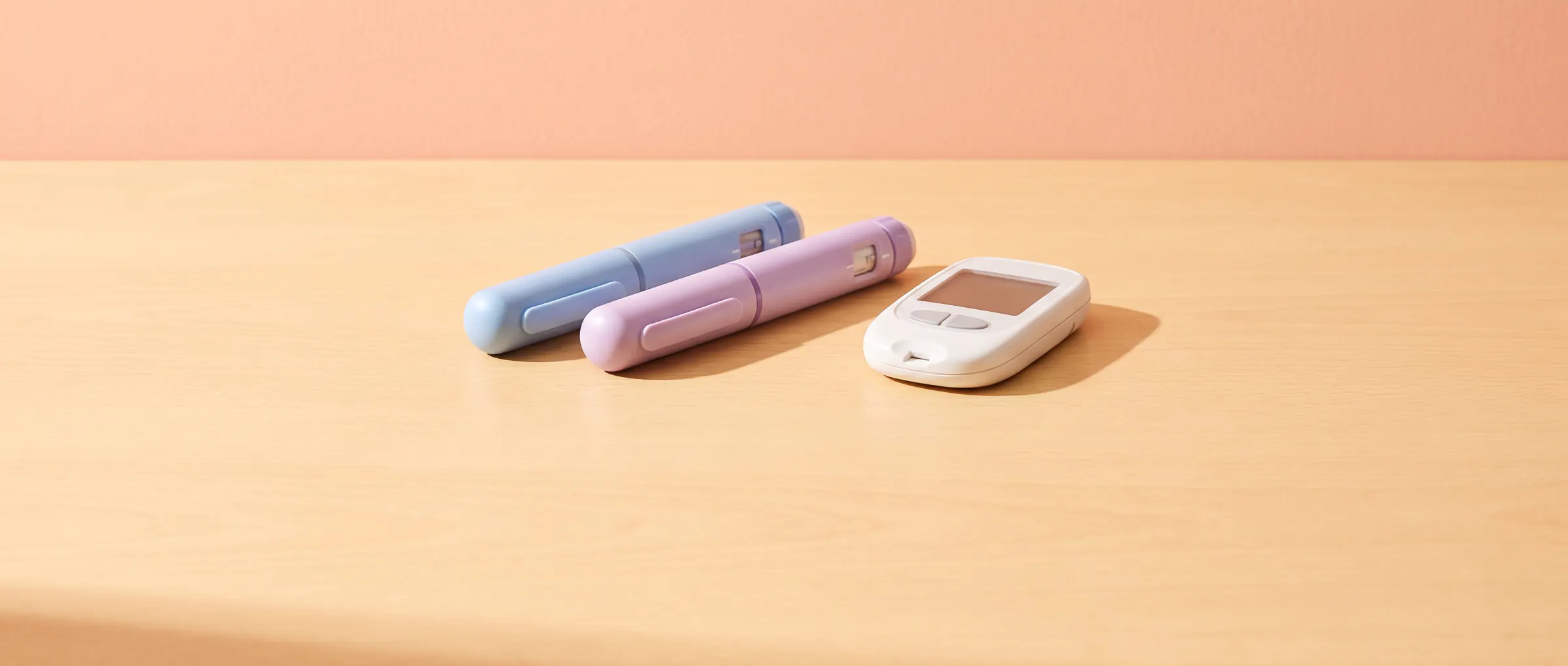 Two plain injection pens, one blue and one lilac, on a sunny table beside a small glucose meter